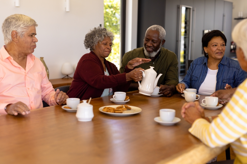 Multiracial,Senior,Friends,Talking,And,Enjoying,Coffee,With,Cookies,On